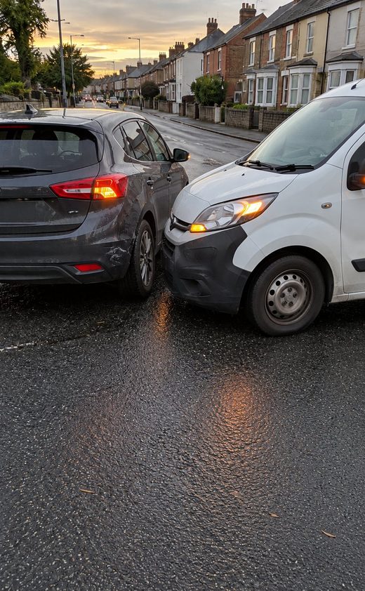 Stamped photo of a grey hatchback and a white van after a low-speed collision on a residential street, shown in the PicAnchor photo viewer
